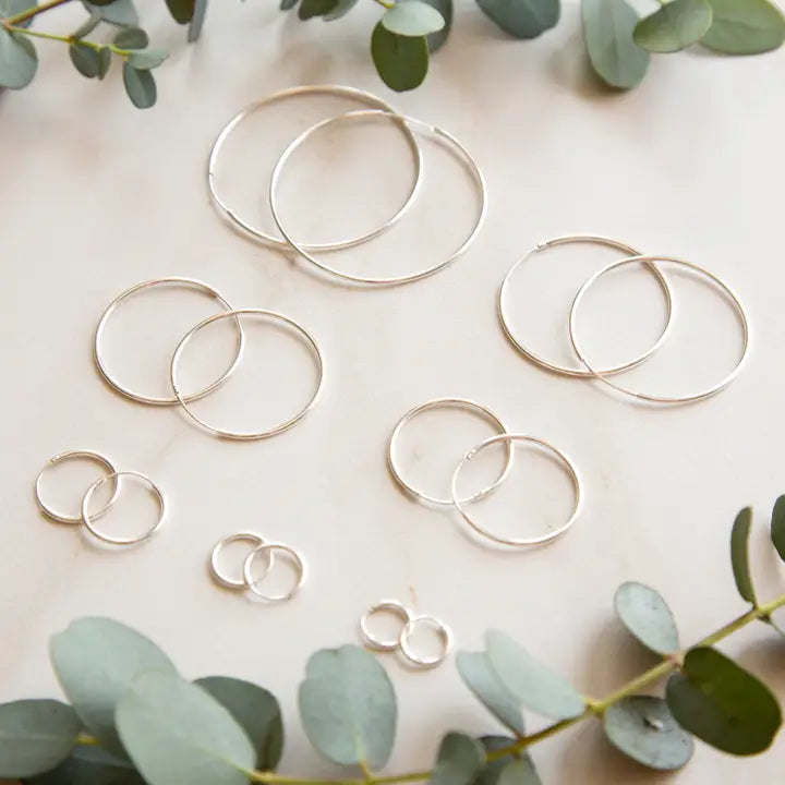 Stowaway silver endless hoops jewelry with sleek circular design and polished finish, hanging against a neutral background.